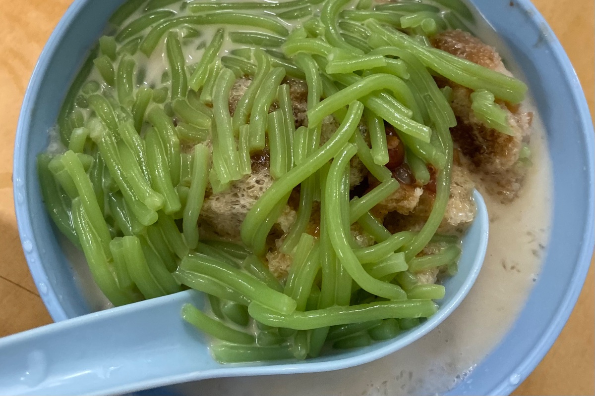 The Penang version is served as a spoonful bowl of finely shaved ice distinguished by the essential addition of plump, creamy stewed red kidney beans alongside a slightly salted coconut milk base that cuts through the rich palm sugar syrup. (Photo Credit: Jaclene Liew)
